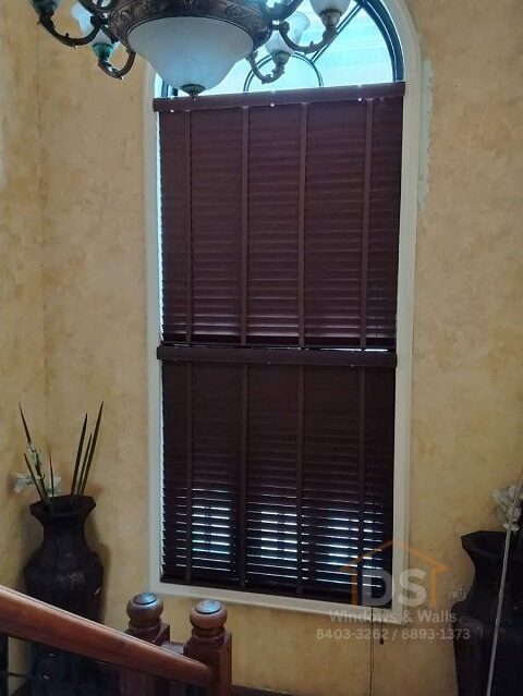 Custom real wood blinds on an arched staircase window in Makati